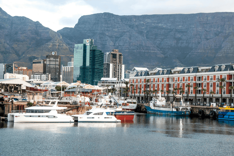 Cape Town's V&A Waterfront harbor with docked boats and Table Mountain in the background.