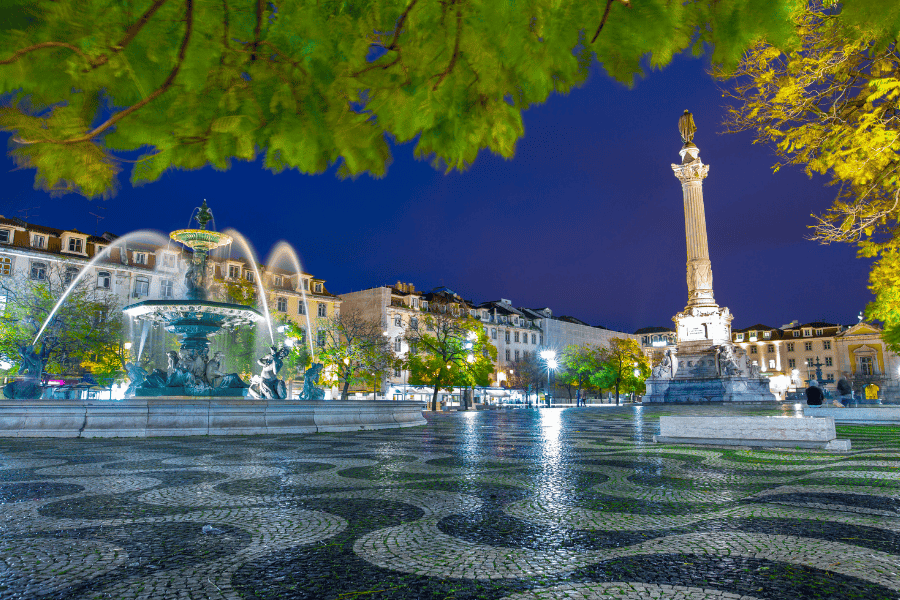 One of the most beautiful squares in Europe surrounded by jacaranda trees, stylish lanterns. Rossio Square(Praça Dom Pedro IV, Praça do Rossio) Lisbon, Portugal.