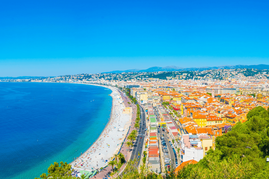 A vibrant, high-angle panoramic view of Nice, France, showcasing the sweeping curve of the Baie des Anges (Bay of Angels).