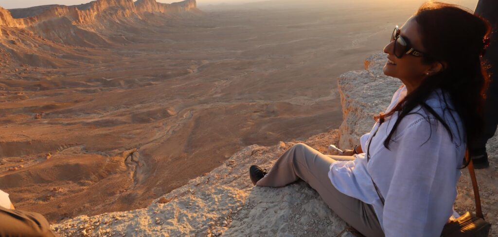 Angela Jane looking out over the escarpment at the Edge of the World, Saudi Arabia, at sunset
